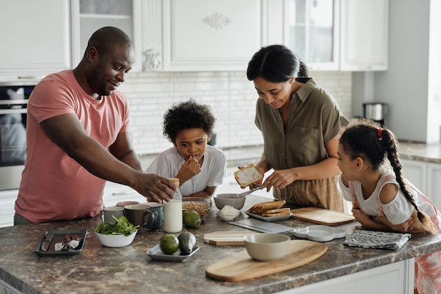 parents with two small children cooking together